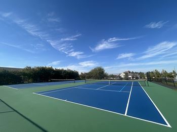A tennis court with blue and green colors under a clear sky.